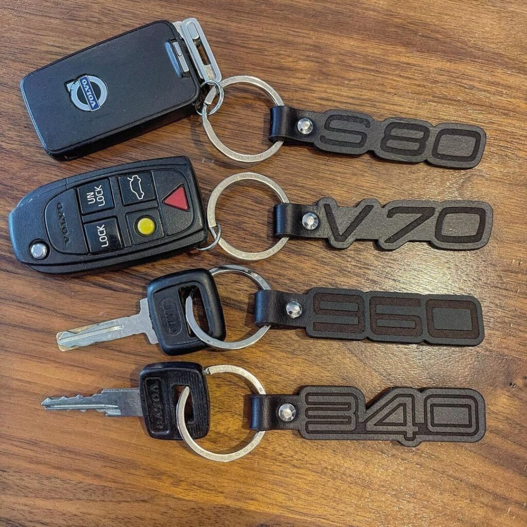 Four car keys with brown leather key fobs embossed with Volvo model numbers.