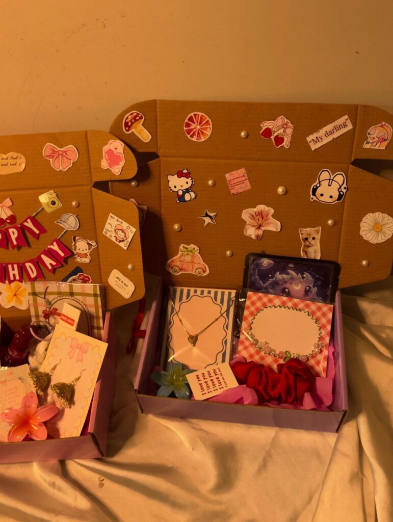 Two decorated purple gift boxes filled with jewelry, accessories, and cute stickers.