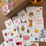Handmade cards with cute illustrations and small gifts next to a decorated box.