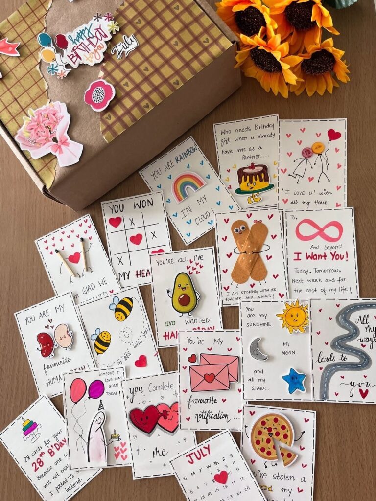 Handmade cards with cute illustrations and small gifts next to a decorated box.