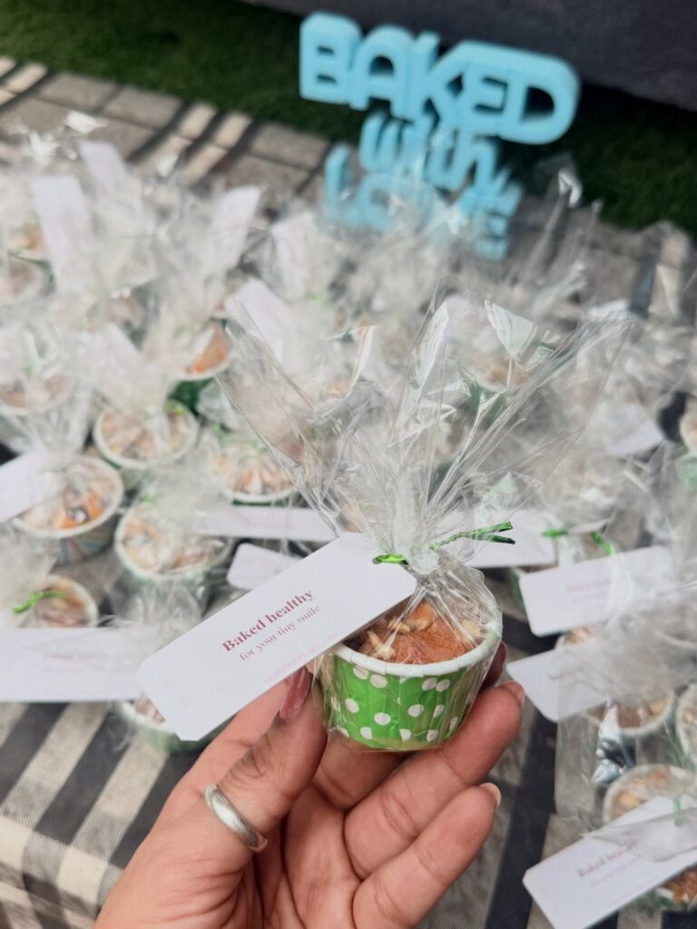 Hand holding a cellophane-wrapped muffin with a tag among many other treats.