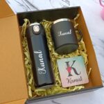 Personalized black water bottle and mug in a gift box with yellow filler.