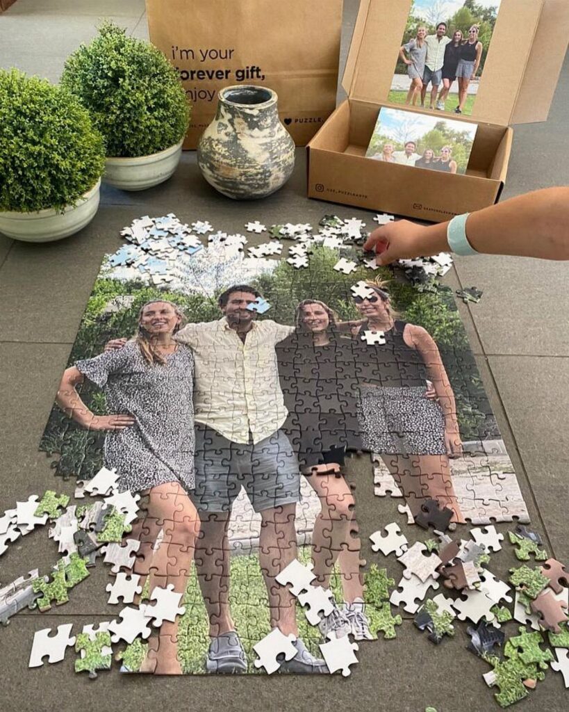 Partially completed jigsaw puzzle of a family photo on a grey tiled floor.
