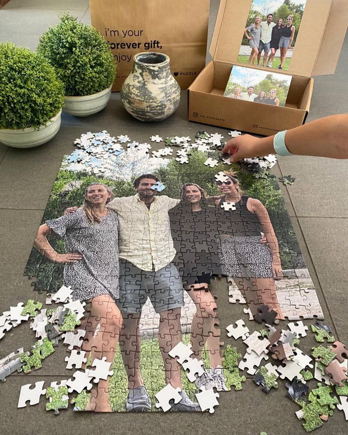 Partially completed jigsaw puzzle of a family photo on a grey tiled floor.
