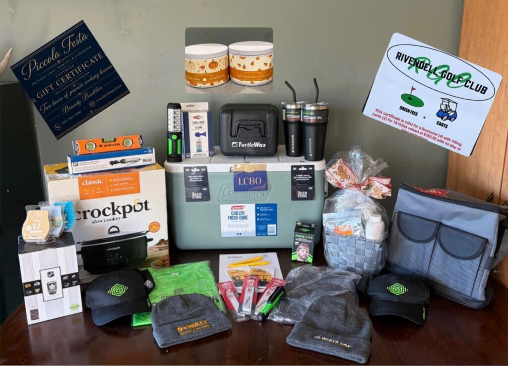Assorted raffle prizes including a slow cooker, cooler, hats, and gift certificates on table.