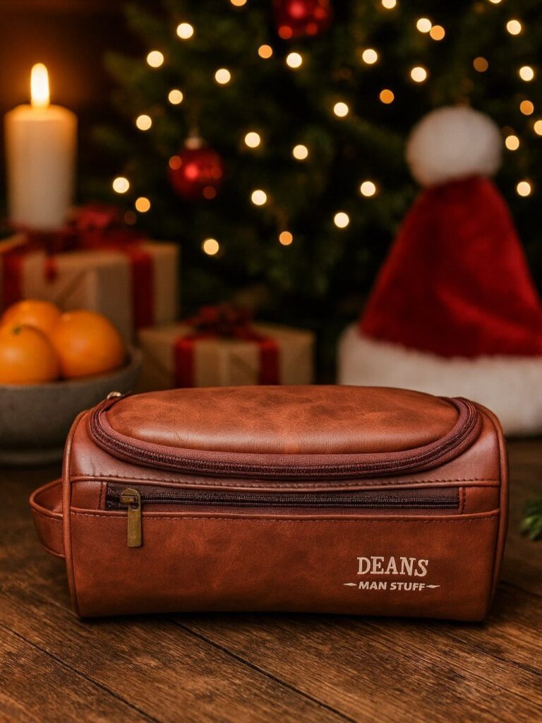 Brown leather travel wash bag with personalized text on a festive wooden table