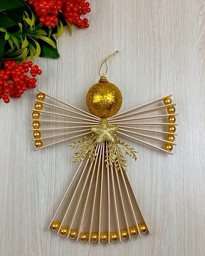 Handmade angel ornament made from wooden skewers and gold beads on light wood.