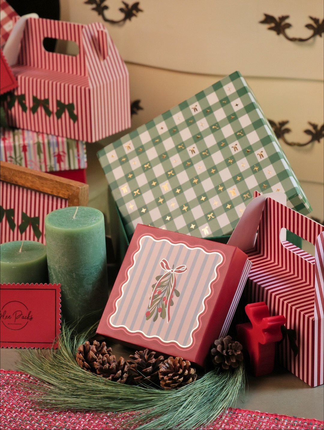 Christmas gift boxes in red and green patterns with candles and pinecones