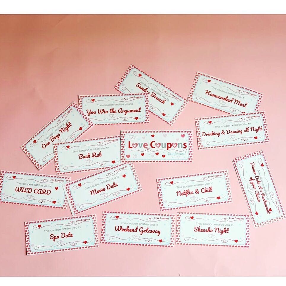 Handmade love coupons with red borders scattered on a light pink background.