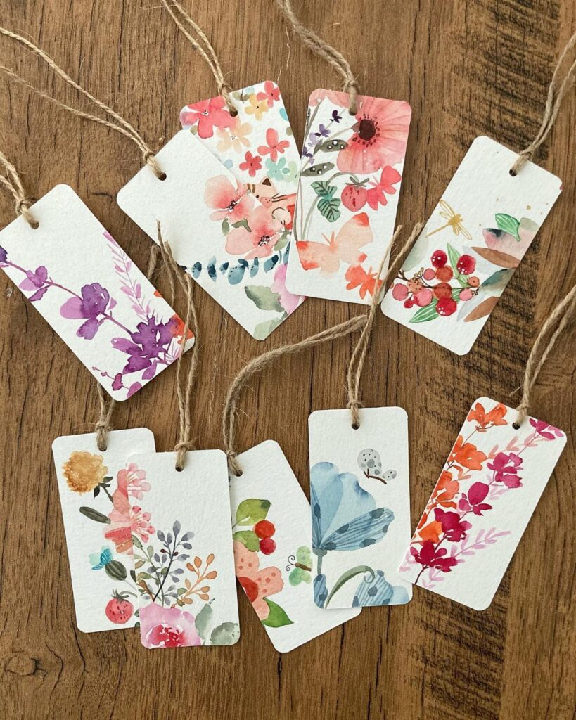 Watercolor floral gift tags with twine strings on a wooden background
