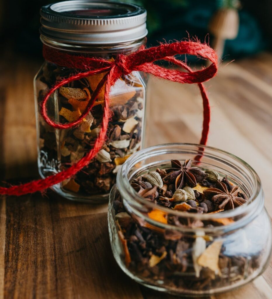 Mulling spices in glass jars with a red bow on a wooden table