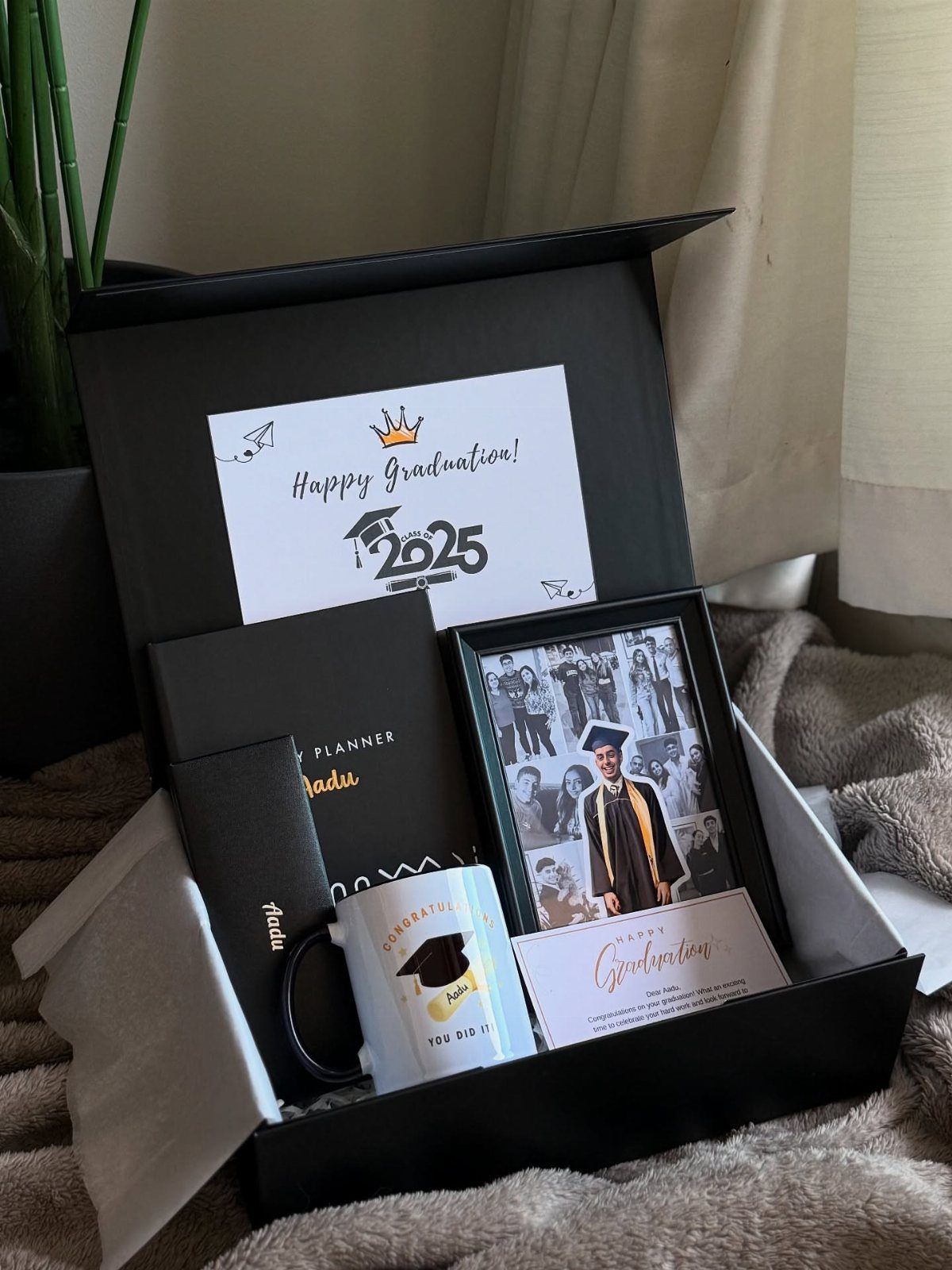 Graduation gift box with a framed photo, themed mug, notebook, and greeting card.