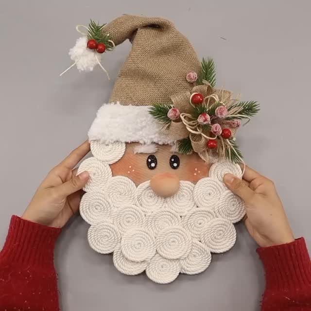 Handmade Santa Claus decoration crafted from burlap and white yarn coils held by hands.