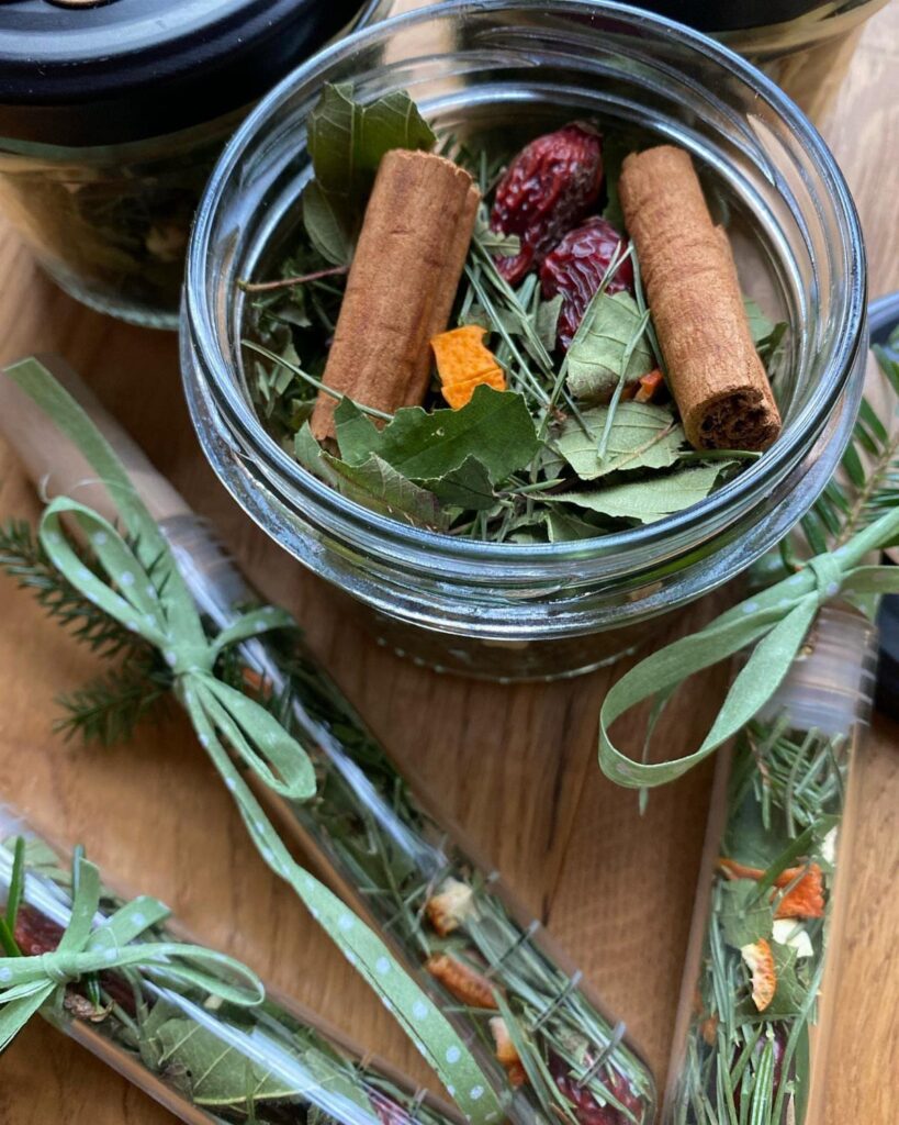 Dried cinnamon sticks and botanicals in a glass jar and ribbon-tied tubes.