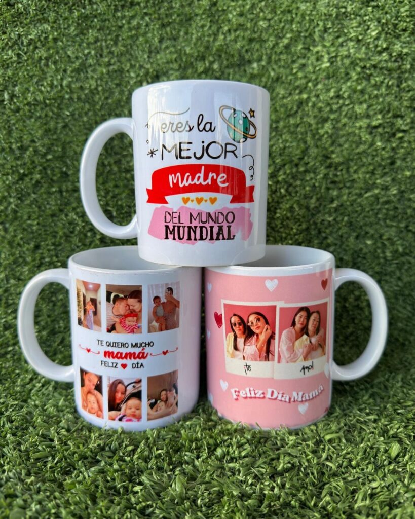 Three personalized ceramic mugs with photos and Spanish text on green grass.