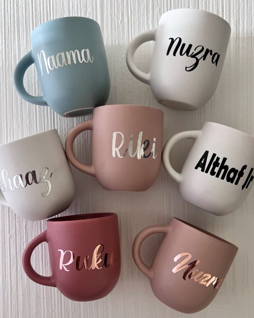 Personalized matte ceramic mugs in various colors with names written in cursive script.