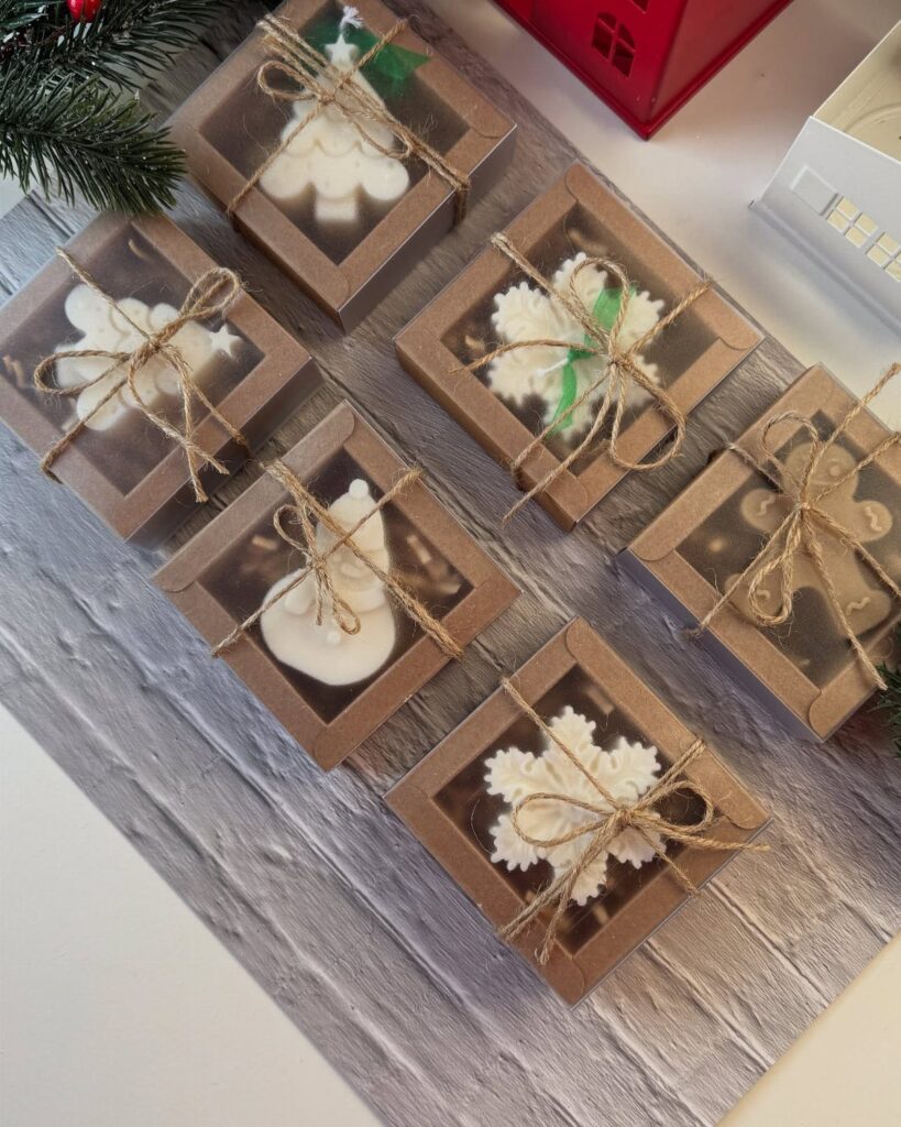 Winter-themed treats in small brown gift boxes tied with twine on wooden surface