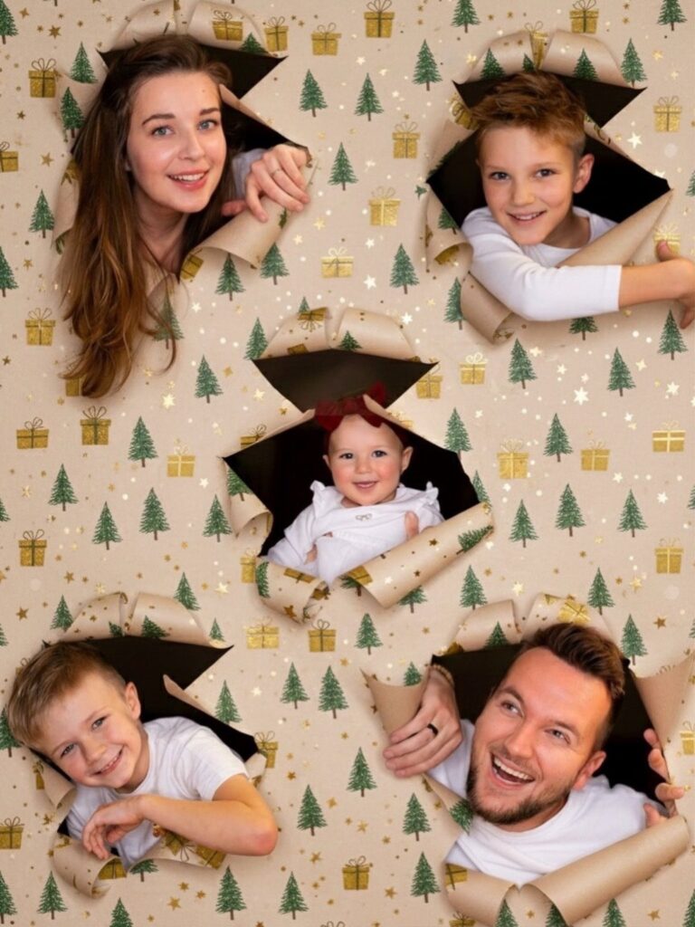 Family peeking through holes in Christmas wrapping paper for a holiday card photo.