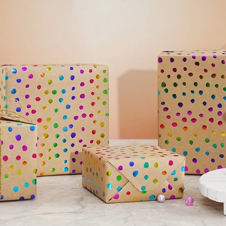 Brown kraft paper wrapped gift boxes decorated with colorful iridescent polka dots.